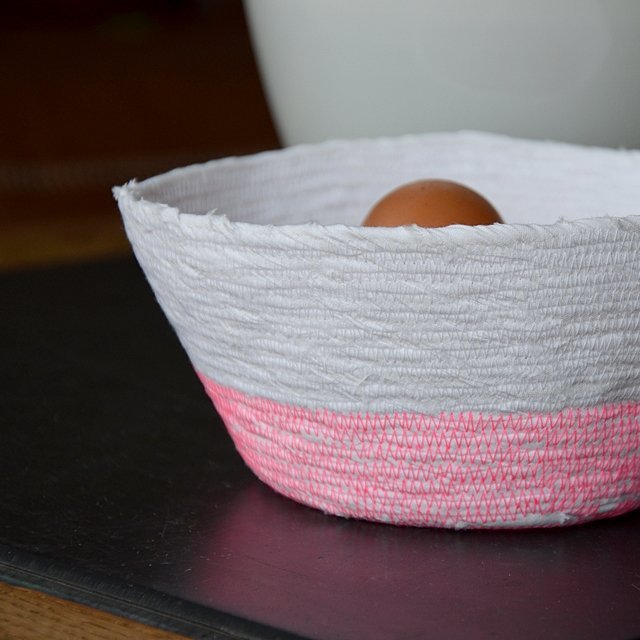 Aus Stoffresten genähtes Körbchen in weiß und neon pink. Ein Ei guckt heraus.